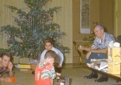 My father (cigarette in hand) calling me on my toy telephone. Mother looks on, as does a gentleman I don't recognise --- cocktail in hand.