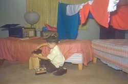 Baba (my maternal grandfather) loved to build make-believe forts for me, using rope and blankets. Here I am with a fort, but I seem to be preoccupied with the shining of shoes. I think the radio (is that what it is?) in the background is amazing.